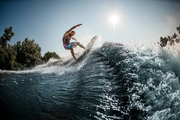 Schöne Aussicht auf die große plätschernde Welle und Mann balanciert darauf auf Foilboard — Stockfoto