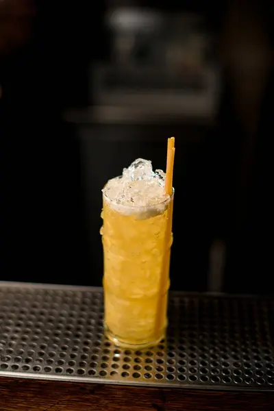 Vaso lleno de hielo y cóctel amarillo brillante con pajitas para beber en el bar — Foto de Stock