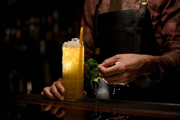 Skvělý výhled na sklo plné ledu a koktejlu s pitnou slámou a mužskou ruku s mokrými mátovými listy — Stock fotografie
