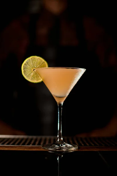 Martini glass with tasty cocktail decorated with slice of lemon on bar counter — Stock Photo, Image