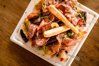 Ekmek çubuklu lezzetli et tabağı, jambon, masada beyaz tabakta salam dilimleri..