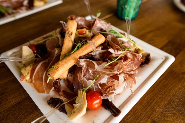 Enfoque selectivo de plato de carne con palitos de pan, jamón, rebanadas de salami en plato blanco en la mesa. — Foto de Stock