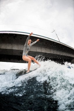 Atletik ve esnek kadın uyanma tahtasında ustalıkla dengede duruyor..