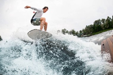 Genç sporcu su sıçratan dalgaların üzerinden ustaca atlıyor..