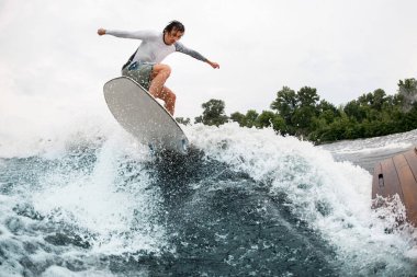 Yakışıklı adam eğleniyor ve yaz günü sörf tahtasına atlıyor..