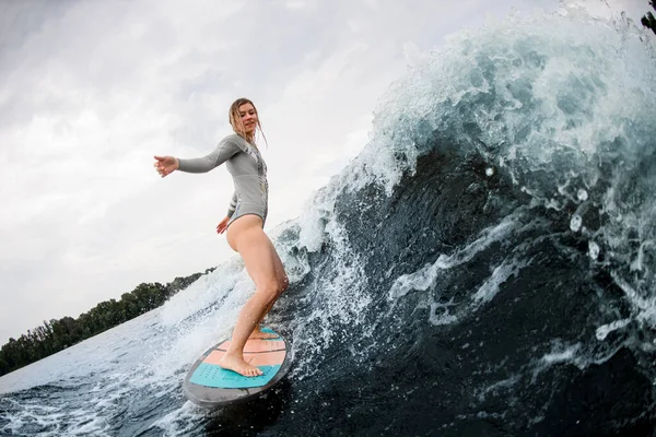 Mujer mojada en traje de neopreno gris paseos en wakesurf abajo en enorme salpicadura ola de río —  Fotos de Stock