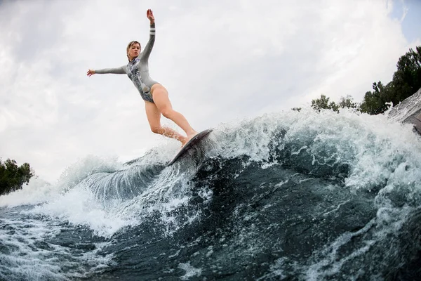 Grande vista su enorme onda spruzzante e donna di energia su wakesurf cavalca giù su di esso — Foto Stock