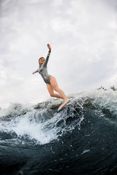 Vue fabuleuse sur d'énormes éclaboussures de vague et de l'énergie femme sur wakesurf monte sur elle — Photo