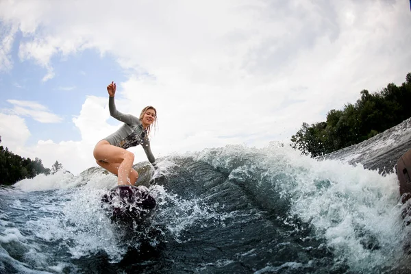 Wakeboard 'daki gülümseyen genç sarışın kadın büyük su dalgalarıyla aşağı iniyor.. — Stok fotoğraf