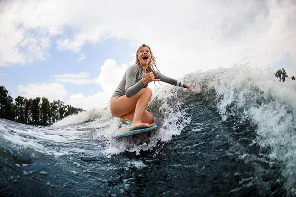 Femme heureuse descend la vague assise sur un wakeboard. Wakesurf sur la rivière. Loisirs d'été — Photo