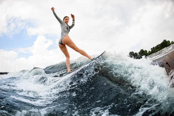 Attrayant flexible femme habilement équilibrage sur vague sur planche de wakesurf. — Photo