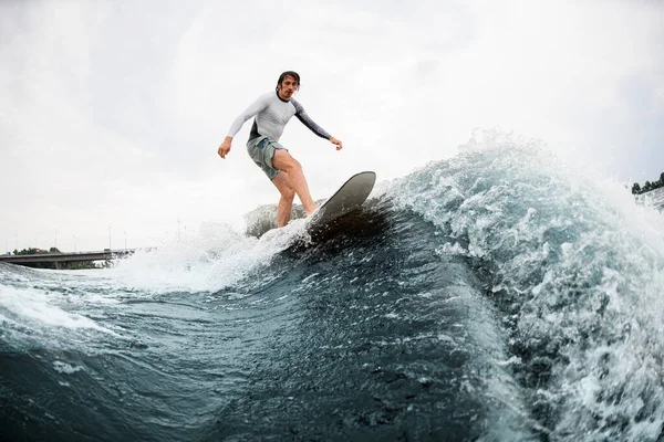 Aktiver Sportler balanciert gekonnt auf Welle auf Wakesurfbrett. — Stockfoto