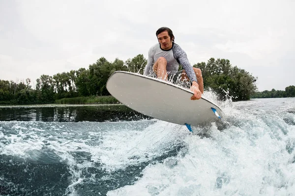 Tipo enérgico con tabla wakesurf volar sobre salpicaduras de olas del río. —  Fotos de Stock