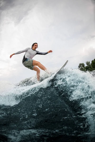 Deportista activo hábilmente montar en ola en tabla wakesurf. — Foto de Stock