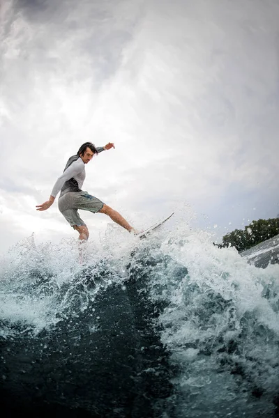 Actieve sporter vakkundig balanceren op golf op wakesurf board. — Stockfoto