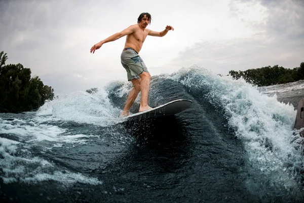 Aktiver Sportler reitet auf dem Wakesurfbrett die Welle hinunter. — Stockfoto