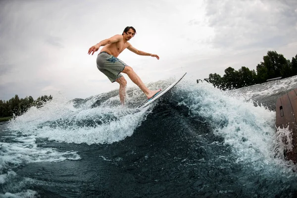 Pria energi sportif naik turun gelombang percikan di papan wakesurf. — Stok Foto