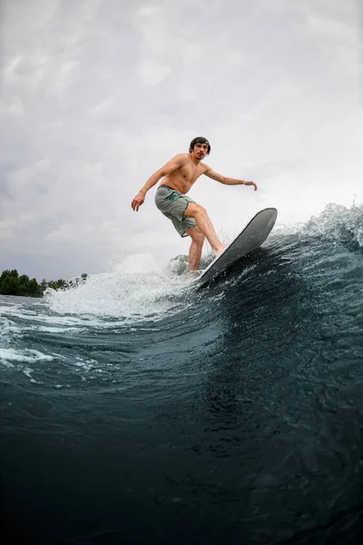 Schöner Mann auf dem Wakesurfbrett und Flusswelle reitend an einem Sommertag — Stockfoto