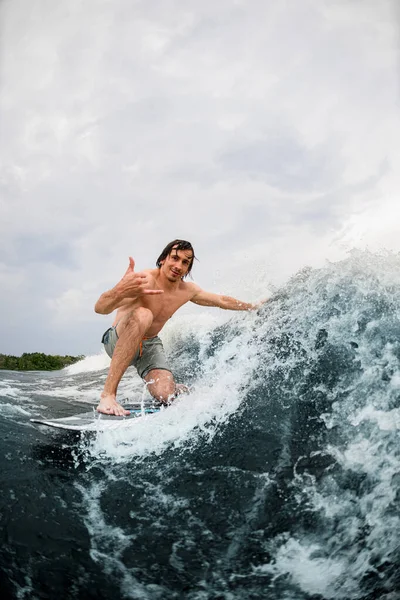 Homem ativo monta a onda no wakeboard estilo surf e toca a onda com uma mão — Fotografia de Stock