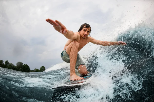 Close-up de homem molhado equilibrando no wakeboard estilo surf e tocar a onda com uma mão. — Fotografia de Stock
