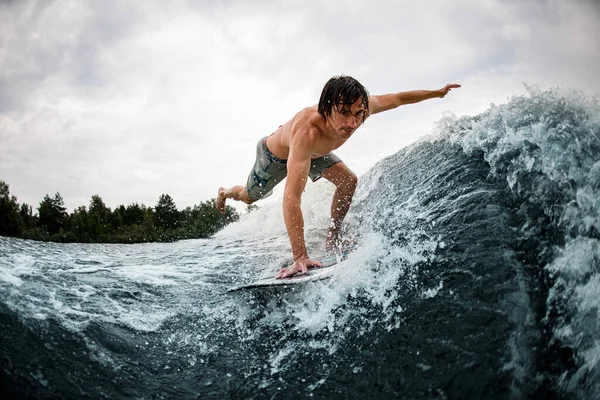 Manusia menyeimbangkan on wake surfing board on wave with stretching his leg and hand — Stok Foto