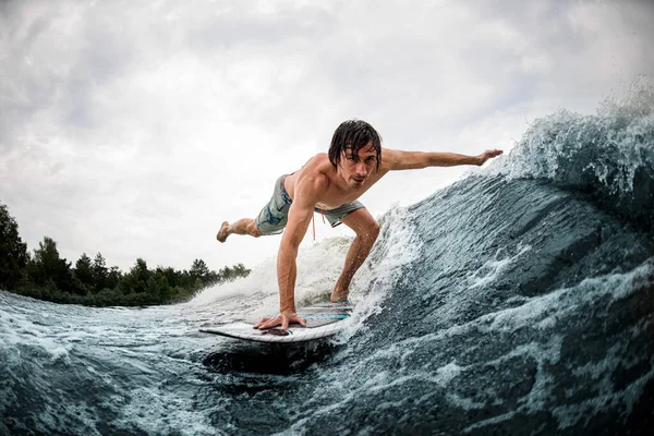 Спортсмен робить трюк балансування на дошці для серфінгу на хвилі з розтягуванням ноги і руки — стокове фото