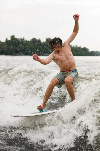 Atlético ativo homem tentando ficar em wakesurf bordo em espirrar onda — Fotografia de Stock