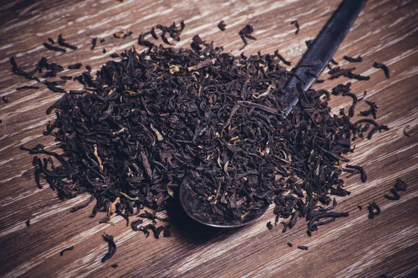Černý čaj, sušené listy na lžíci — Stock fotografie