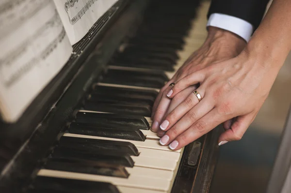 Hands with wedding rings on piano Stock Picture