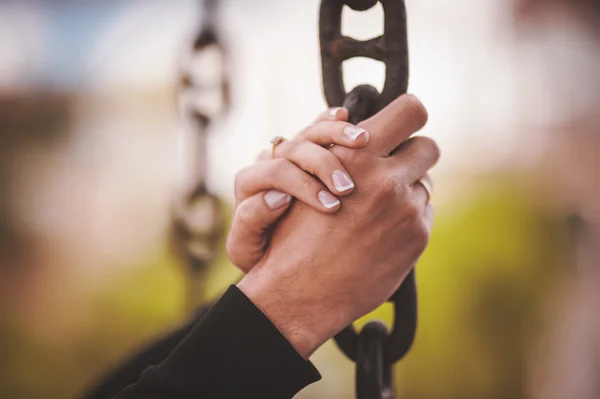 couple holding hand together on chain