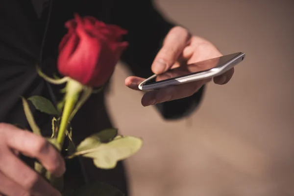 Men holds red rose while calling — Stock Photo, Image