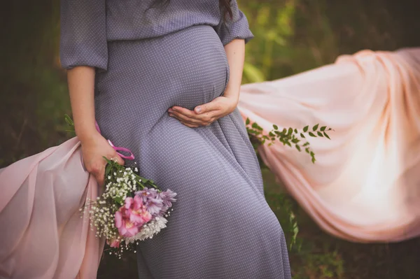 妇女在怀孕时在她的肚子上握着的手 — 图库照片