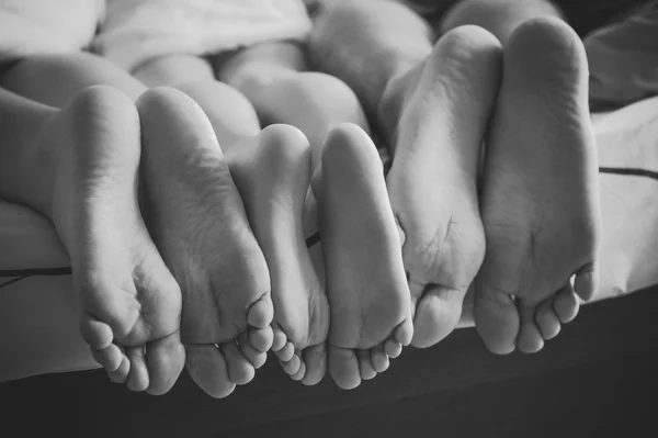 Close up de uma família mostrando seus pés sob as coberturas . — Fotografia de Stock