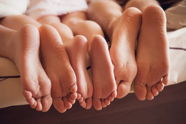 Nahaufnahme einer Familie, die ihre Füße unter der Decke zur Schau stellt. — Stockfoto