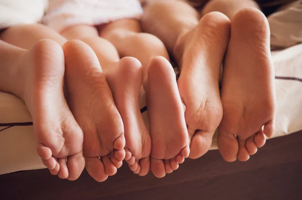 ใกล้ชิดกับครอบครัวที่แสดงเท้าของพวกเขาภายใต้ผ้าห่ม . ภาพถ่ายสต็อกที่ปลอดค่าลิขสิทธิ์