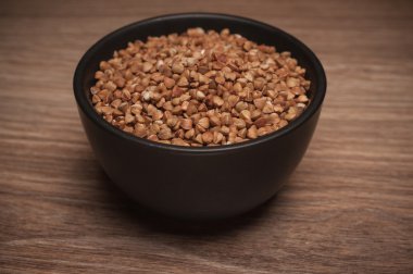 Ahşap arka plan üzerinde siyah kapta buğday. 