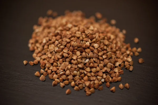 Buckwheat pile on a black stone background — Stock Photo, Image