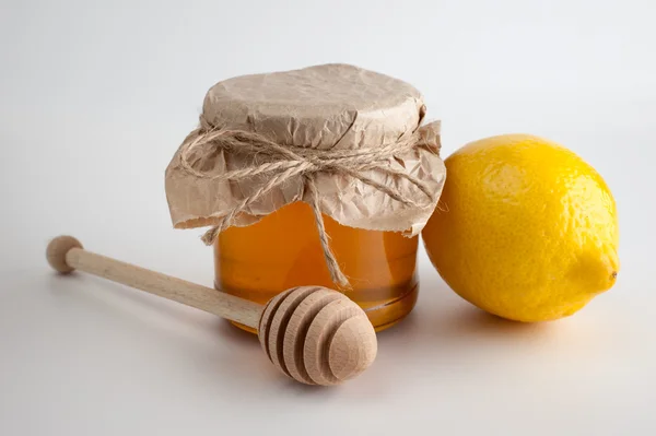 Miel en frasco y limón sobre fondo blanco — Foto de Stock
