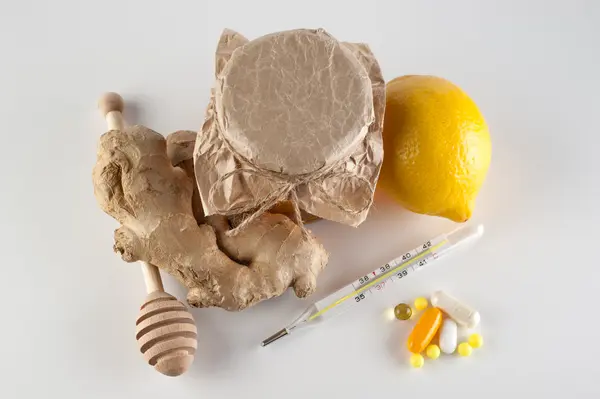 Termómetro, comprimidos e vitaminas VS frasco de mel, gengibre, limão — Fotografia de Stock