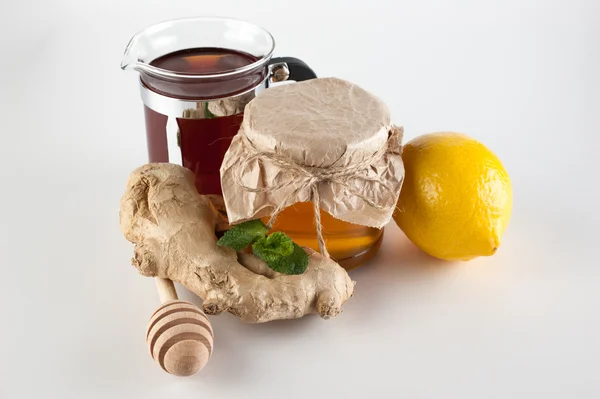 Miel en frasco, taza de té, menta, limón y jengibre sobre un fondo blanco — Foto de Stock