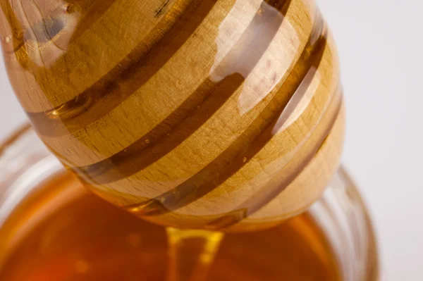 Glass can full of honey and wooden stick in it. — Stock Photo, Image