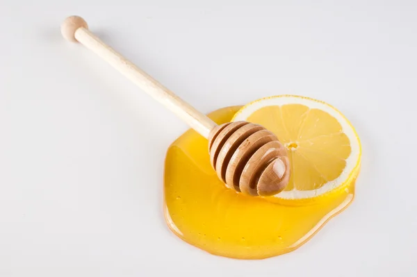 Miel goteando en rebanada de limón aislado blanco — Foto de Stock