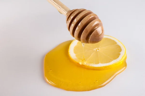 Miel goteando en rebanada de limón aislado blanco — Foto de Stock