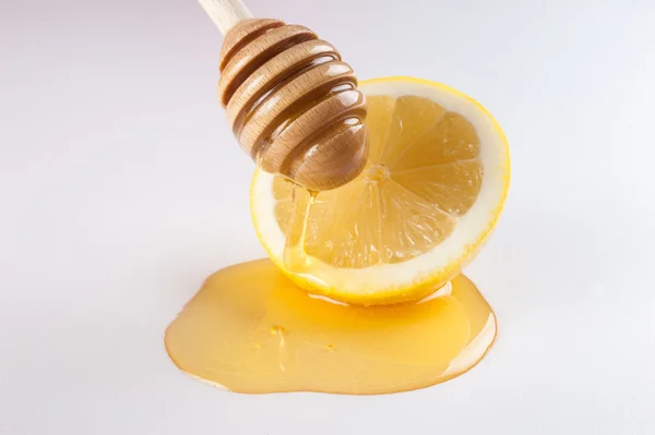 Miel goteando en la mitad de limón aislado blanco — Foto de Stock