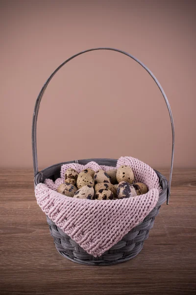 Quail eggs  in a basket with pink knit on wooden background — Stock Photo, Image