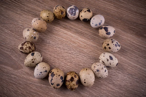Quail eggs in circle on wooden background — Stock Photo, Image