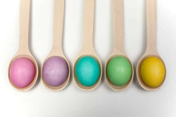 Row of easter eggs on wooden spoons isolated white — Stock Photo, Image