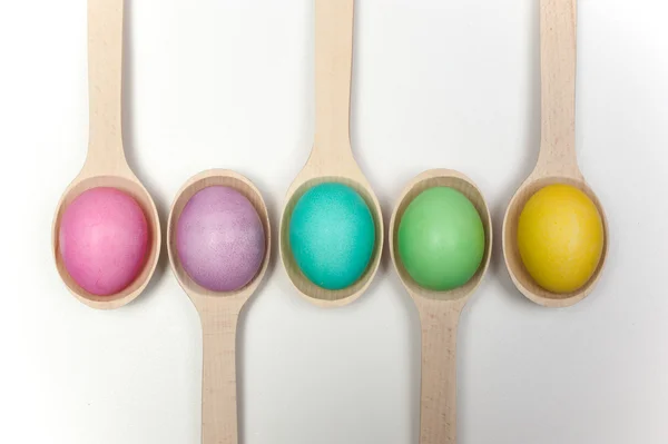 Easter eggs in wooden spoons isolated on white — Stock Photo, Image