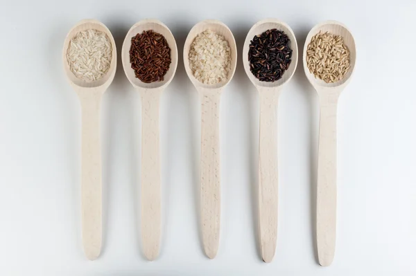 Different kinds of rice in spoons isolated on white background — Stock Photo, Image