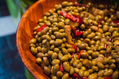 Green olives with pepper and baby corn  in wooden bucket sold on market